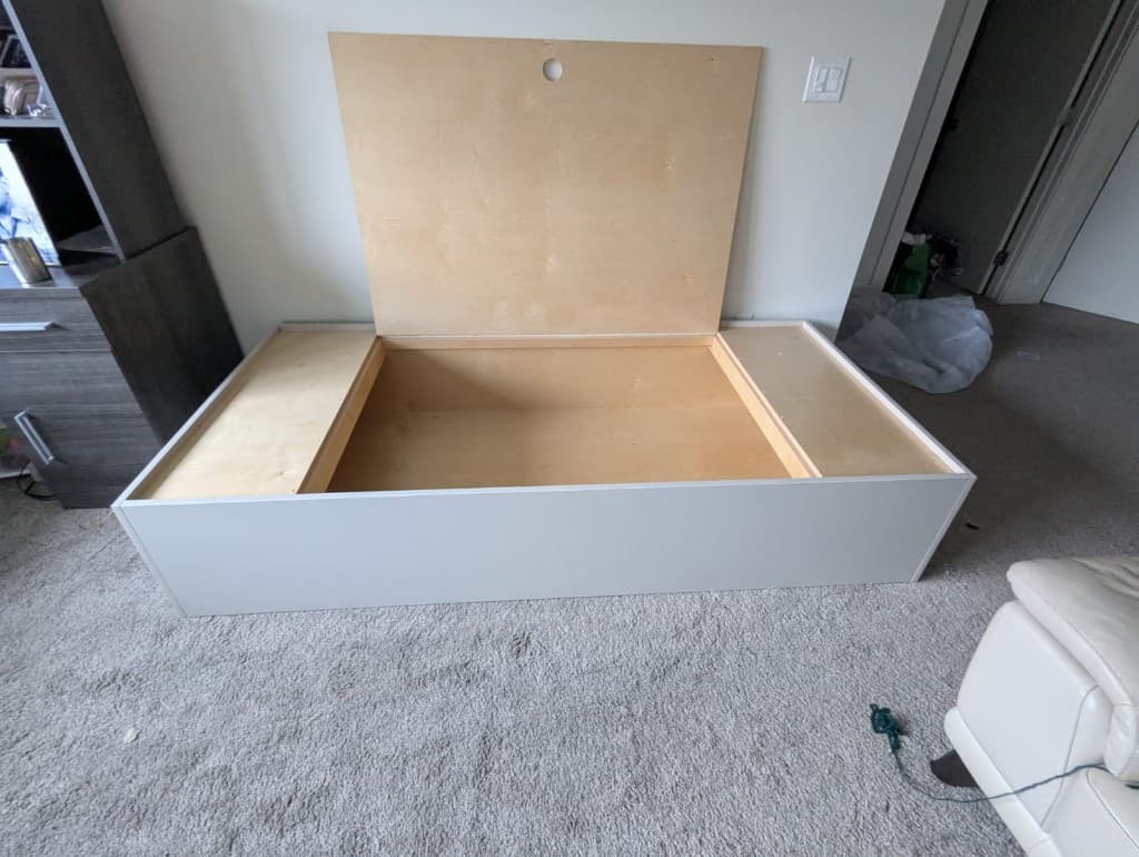 Custom hydraulic lift-top storage box bed with the lid open, showing empty storage interior