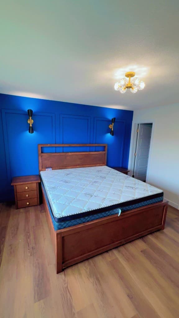 Traditional wood custom bed frame installed against a blue accent wall